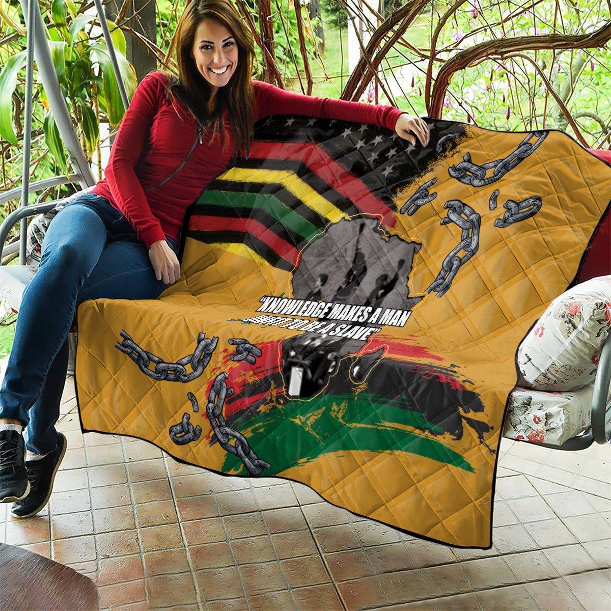 Yellow quilt held up displaying black stars, rainbow bands, chain figures, and map graphic.