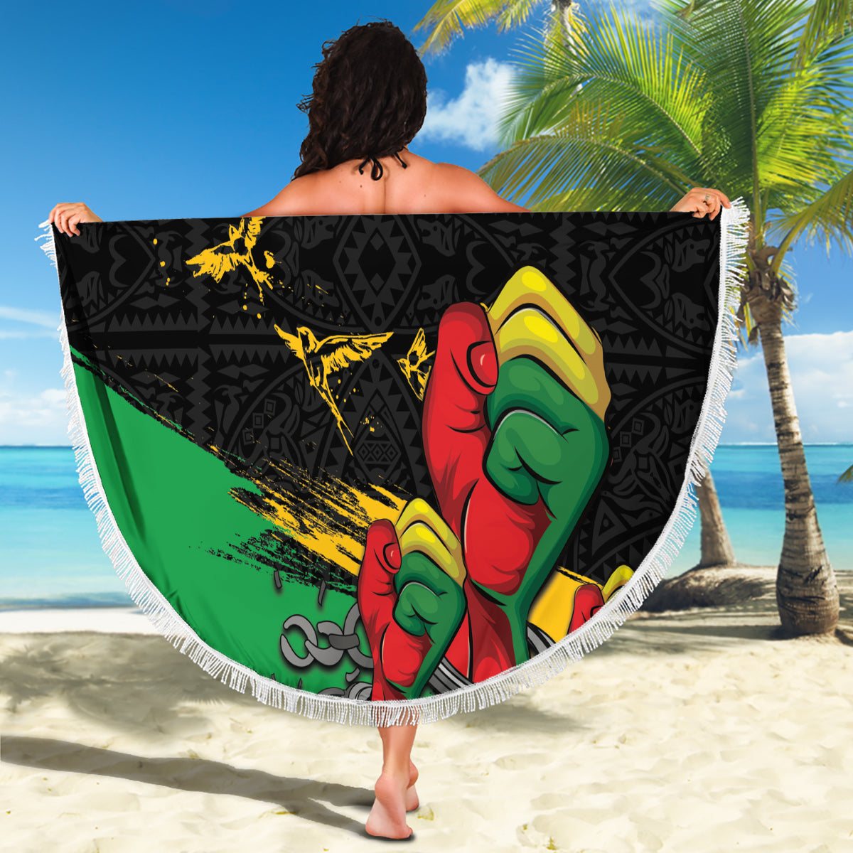 Round fringed beach blanket with raised fist art and 'YOUR TEXT', held up on sand