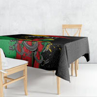 Black tablecloth with bold green, red, and yellow raised fist graphic over ornate pattern.