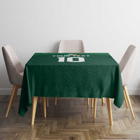Green shamrock-pattern tablecloth on a square table with chairs, centered view