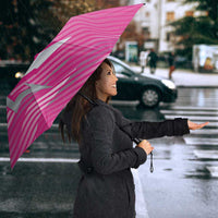 Pink and navy umbrella with Barbados Royals trident crest, held outdoors