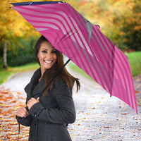 Pink and navy umbrella with Barbados Royals crest, held outdoors in rain