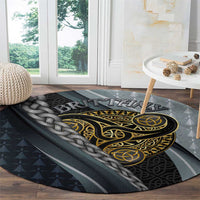 Round grey carpet with gold and black Celtic emblem and braided knot detail along edge.