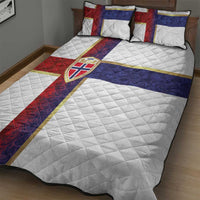 Quilt bed set on bed: white quilt with diagonal red, blue, and yellow flag cross panels