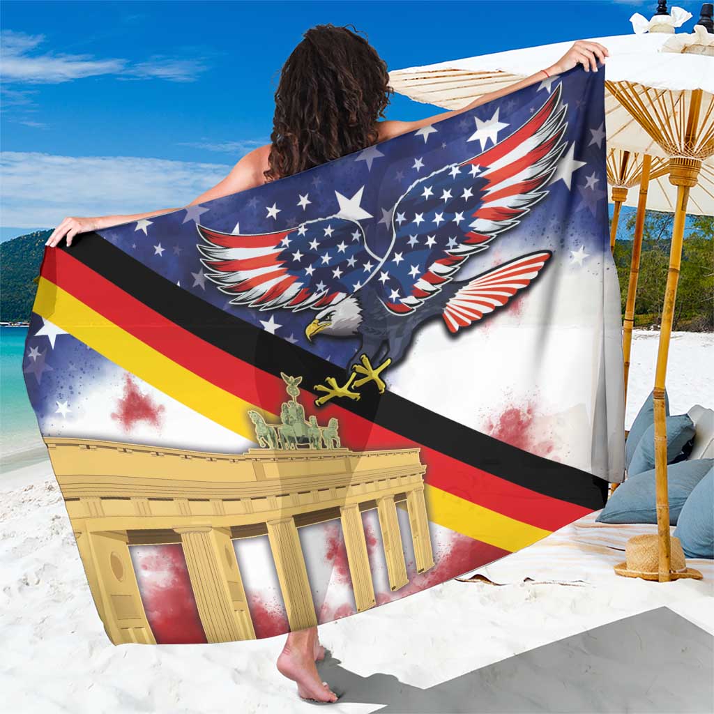 White sarong held close-up with large eagle graphic and Brandenburg Gate over flag stripes