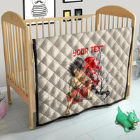 Beige quilt on wooden crib, diamond stitching with red “YOUR TEXT” and samurai cherry blossom art.