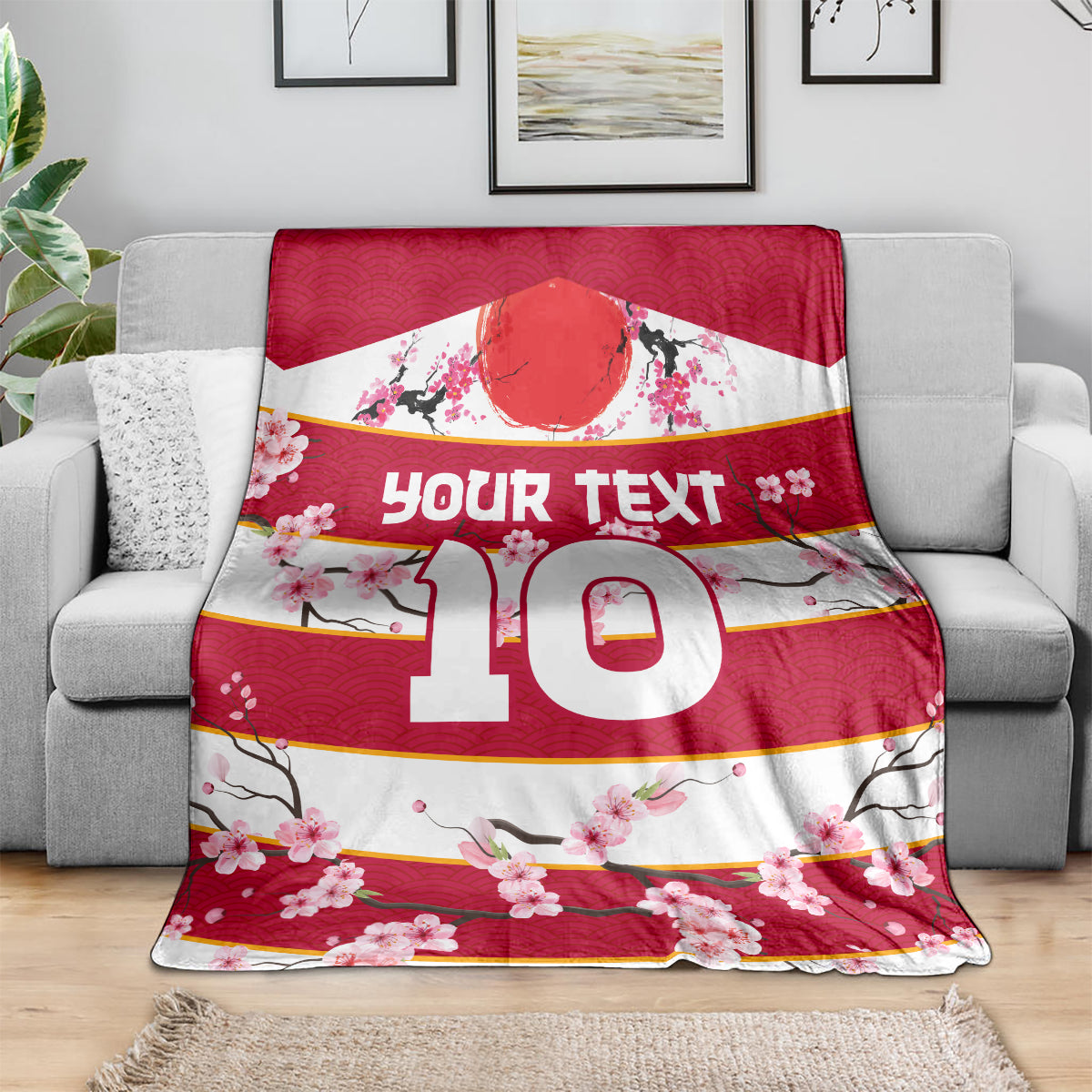 Red rugby blanket on gray sofa, 'Your text 10' and pink sakura blossom print