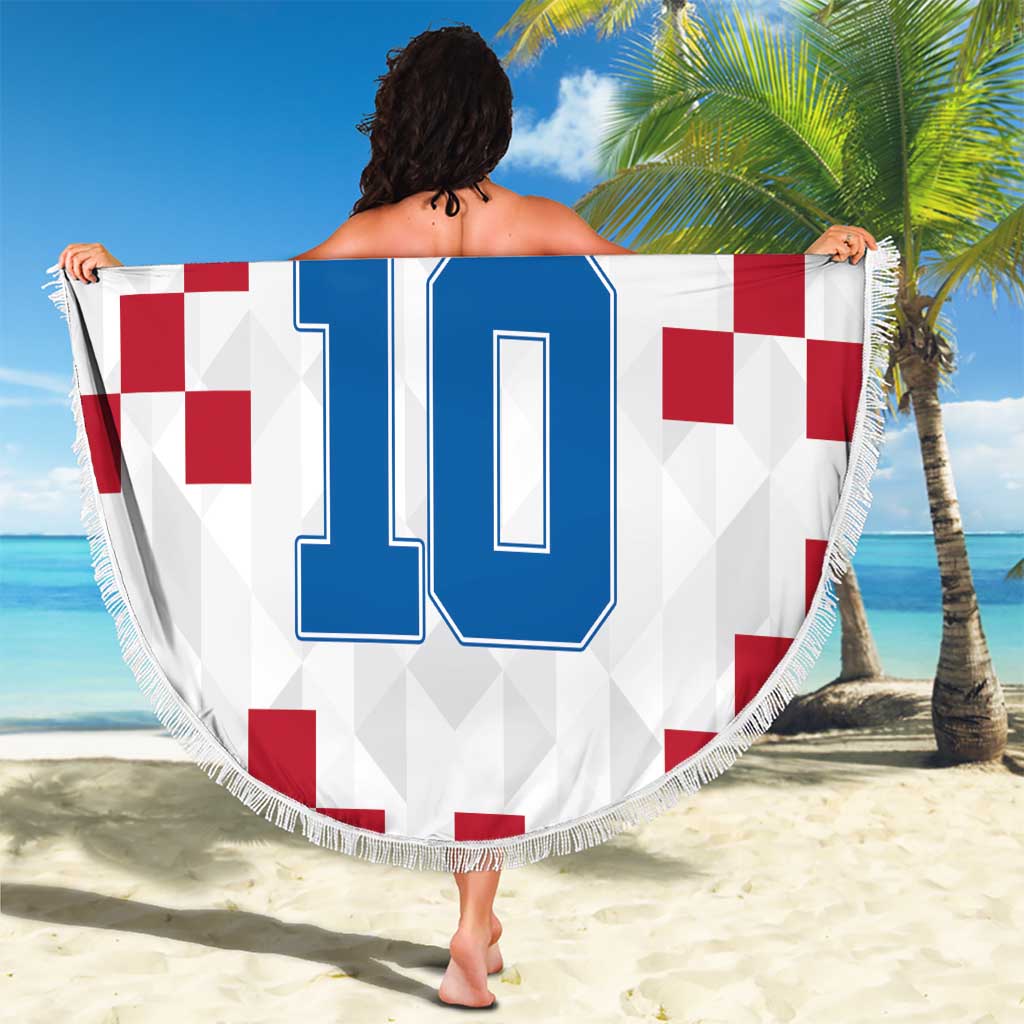 Round Croatia beach blanket with large blue 10 print and fringed edge, held up outdoors