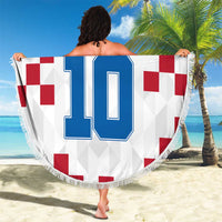 Round Croatia beach blanket with large blue 10 print and fringed edge, held up outdoors