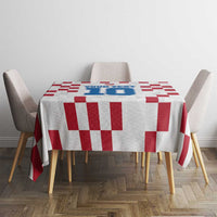 White tablecloth with red checkerboard design and blue emblem on dining table