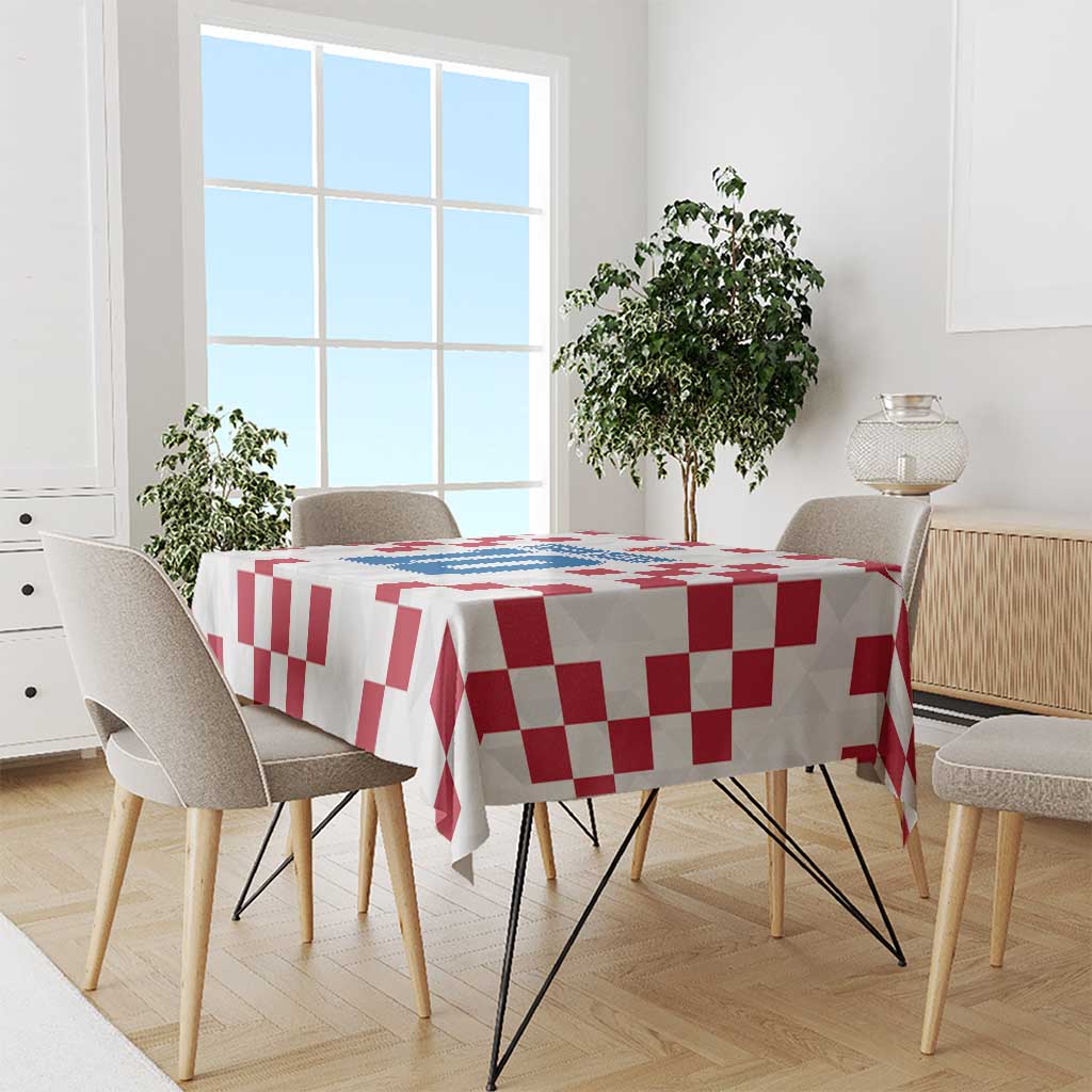 White tablecloth with red checkerboard pattern and blue crest on dining table
