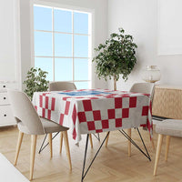 White tablecloth with red checkerboard pattern and blue crest on dining table