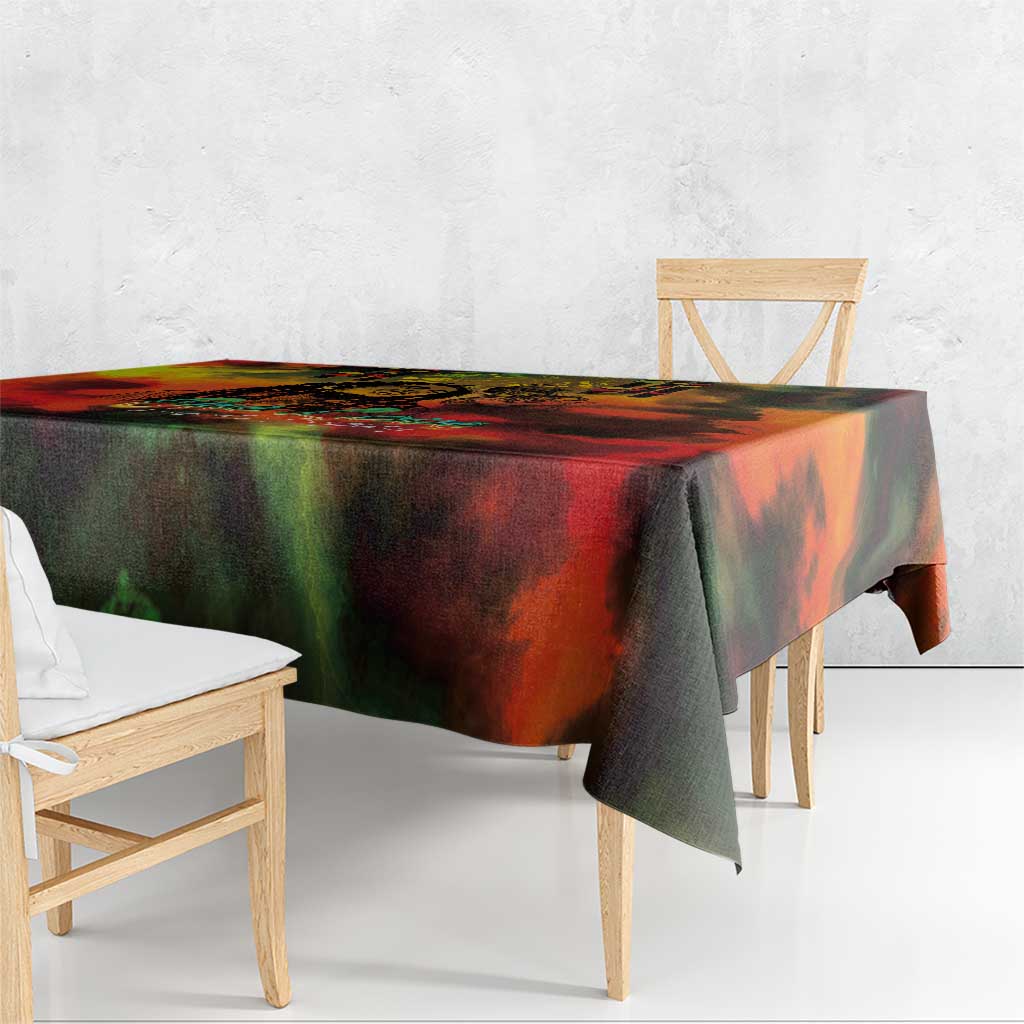 Reggae-themed tablecloth with red, green and black abstract artwork draped over wooden table