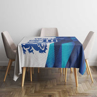 Blue and teal geometric tablecloth draped over dining table with chairs