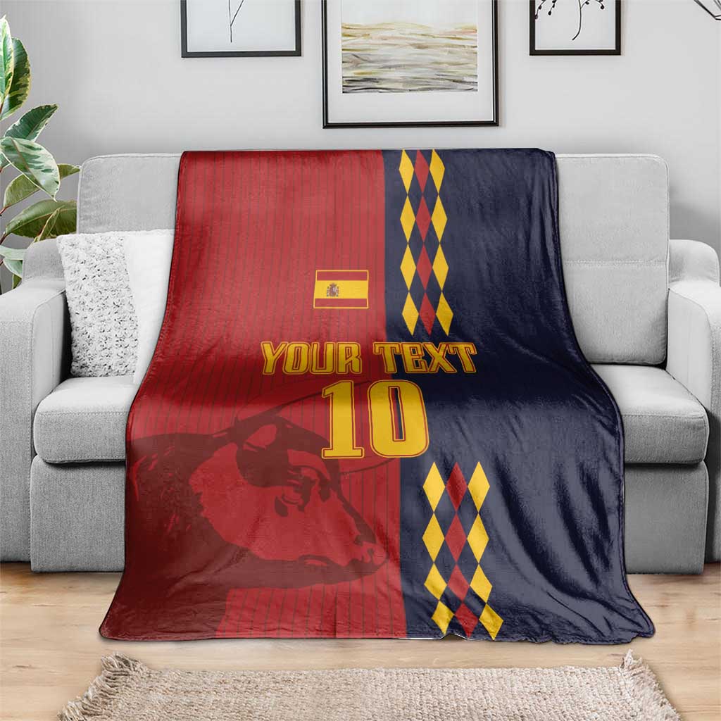 Custom Spain football blanket draped over a sofa, red and navy lion graphic and diamond stripes