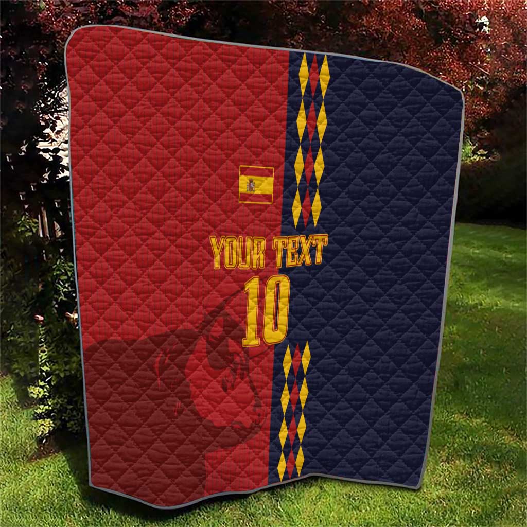 Red and navy diamond-quilt blanket with Spain crest, blue/yellow stripes and '10' outdoors.