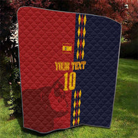 Red and navy diamond-quilt blanket with Spain crest, blue/yellow stripes and '10' outdoors.