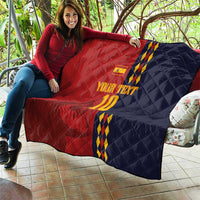 Red and navy diamond-quilt blanket with Spain crest, blue/yellow stripes and '10' held up.