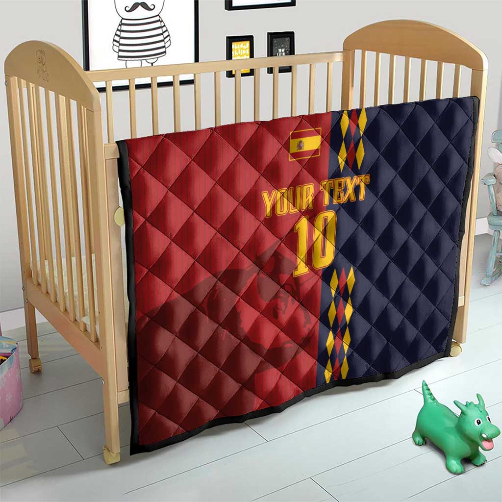 Red and navy diamond-quilt blanket with Spain crest, blue/yellow stripes, '10' on crib.