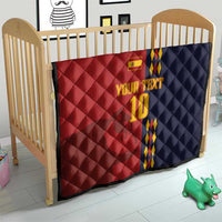 Red and navy diamond-quilt blanket with Spain crest, blue/yellow stripes, '10' on crib.