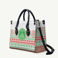 White leather tote bag with black handles, green holiday motif and red pattern