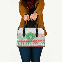 White tote bag with black top handles and festive red-green patterned front