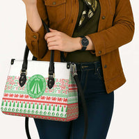White patterned tote bag with black handles and dangling crossbody strap