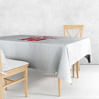 White tablecloth with red emblem across the center, draped on a dining table