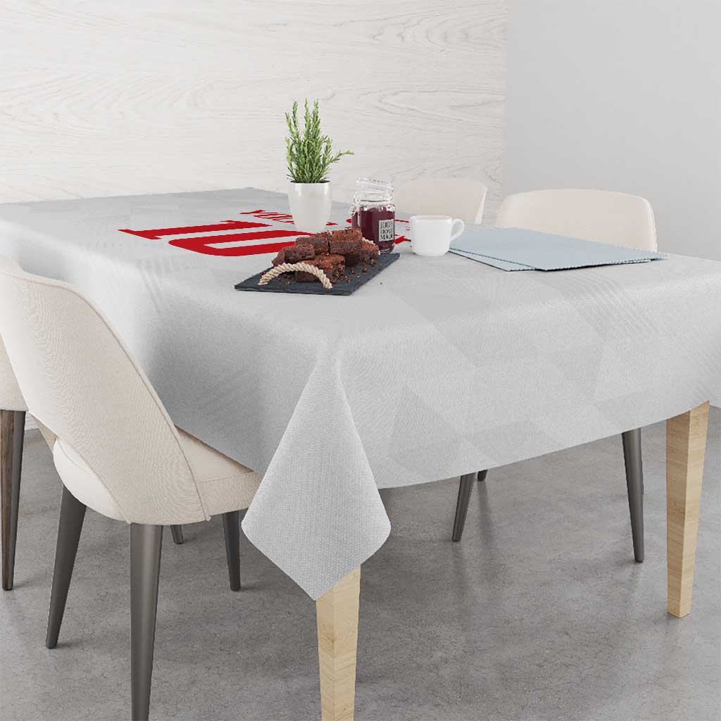 White tablecloth with red emblem across the center on a dining table
