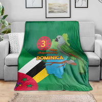 Green Dominica blanket with flag-and-map artwork and parrot, folded over gray couch