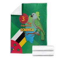 Green Dominica blanket with flag-and-map print beside folded white blankets