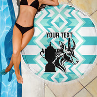 Round beach blanket on poolside with turquoise-and-white chevrons, black crest, fringe