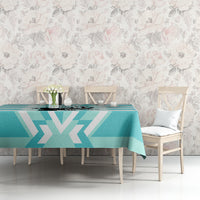 Teal and white geometric tablecloth on dining table against a floral wall