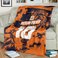 Orange and navy sports blanket with lion graphic and large white 10 on a couch