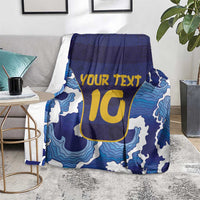 Blue wave-pattern rugby blanket with yellow YOUR TEXT and U-style emblem, draped