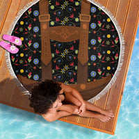 Round beach blanket with black floral print and brown lederhosen suspenders design, fringe edge