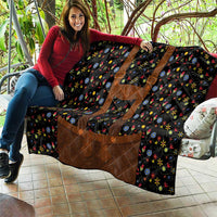 Folded black quilt blanket featuring brown accents and bright floral folk pattern