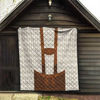 White quilt blanket hanging on a wall with brown lederhosen applique center