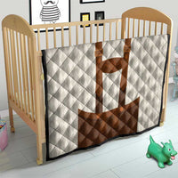 White diamond-quilted baby blanket with brown lederhosen applique on crib