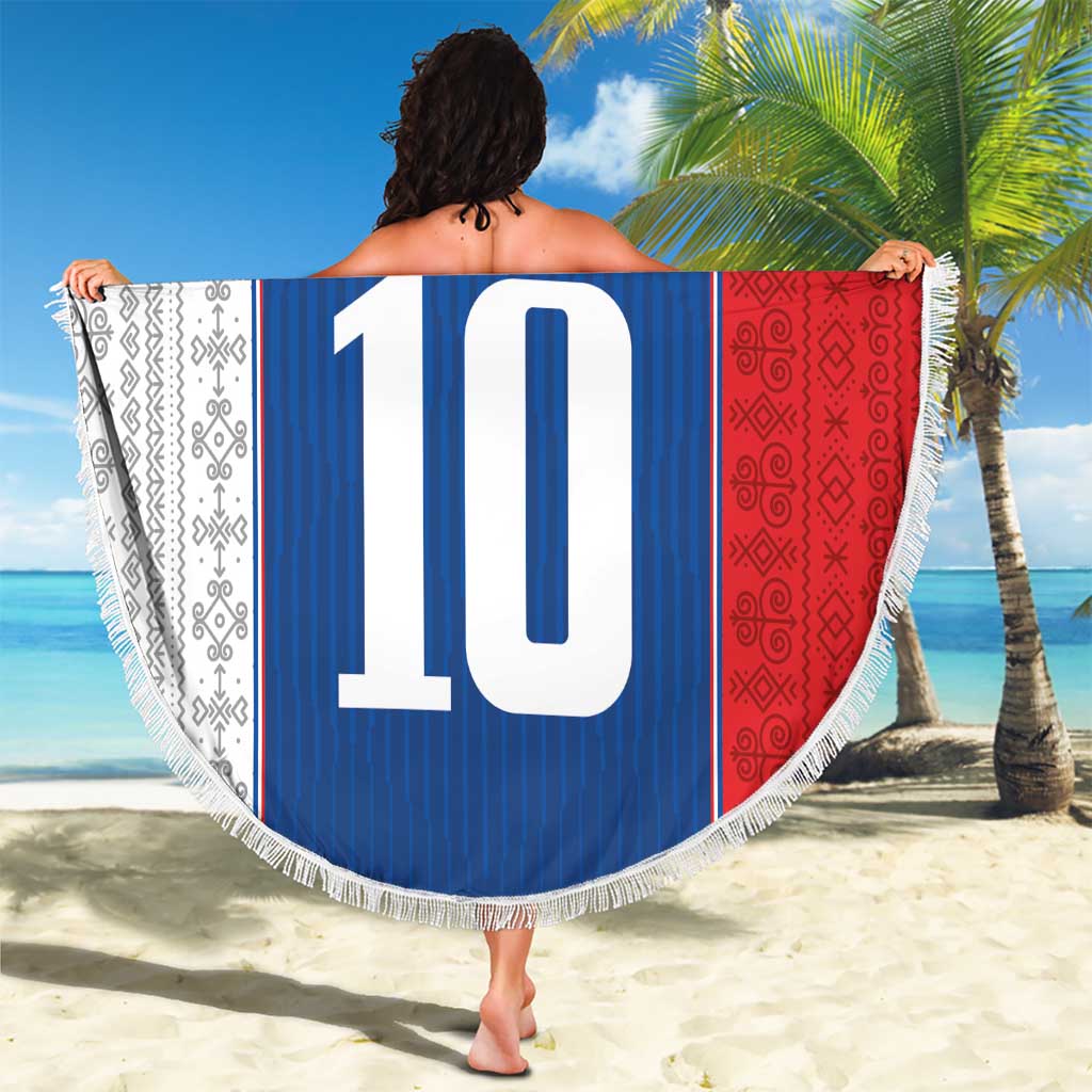 Round beach blanket on sand, blue center with crest and large '10', bordered with white fringe