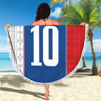 Round beach blanket on sand, blue center with crest and large '10', bordered with white fringe
