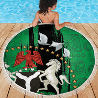 Round beach blanket with white fringe, green-and-black emblem with white dove and horse