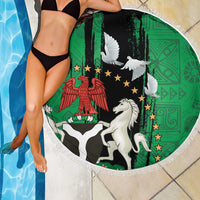 Round beach blanket with white fringe, green-and-black dove emblem with star details