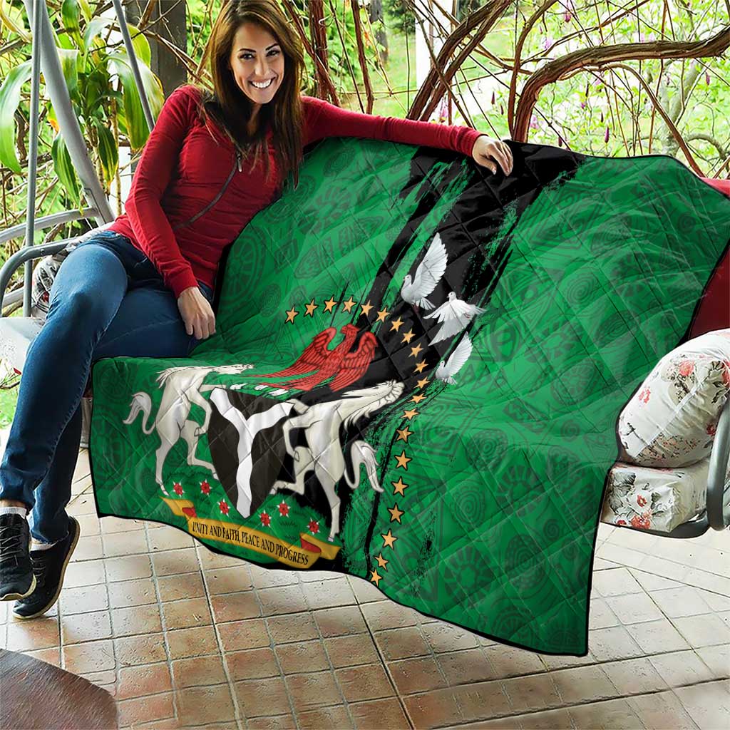 Green quilt being unfolded outdoors: black center with Nigeria emblem and peace dove