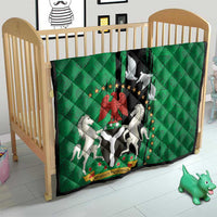Green quilt on baby bed with black center panel, peace dove, and Nigeria emblem