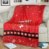 Red personalized holiday blanket draped on sofa with Swiss cross, snowflakes, and plus stripe