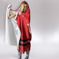 Red hooded blanket with snowflake print and cross-belt stripe, draped over shoulders