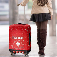 Red luggage cover with Swiss map and cross, 'YOUR TEXT' lettering, standing on wheels