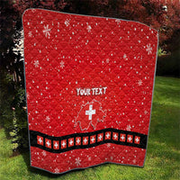 Red quilt with Swiss cross and “YOUR TEXT”, shown outdoors in landscape view