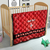Red quilt with Swiss cross and “YOUR TEXT”, placed in wooden crib
